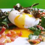 Traditional dandelion leaf salad with bacon bits and poached egg